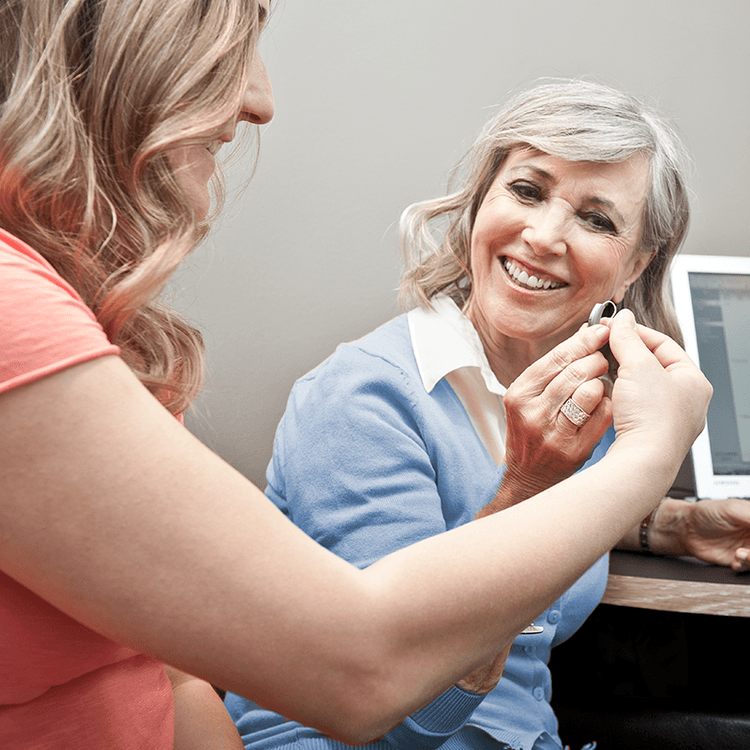 woman handing over small hearing aid for repair