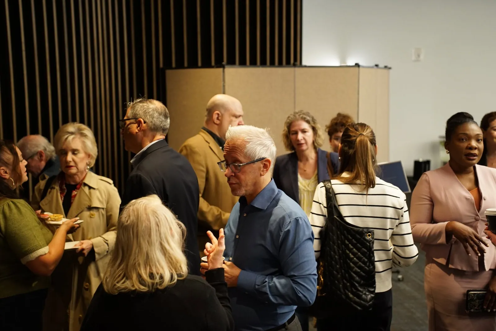 Guests standing and talking in a meeting room before the senior living round table at Frank Residences in San Francisco