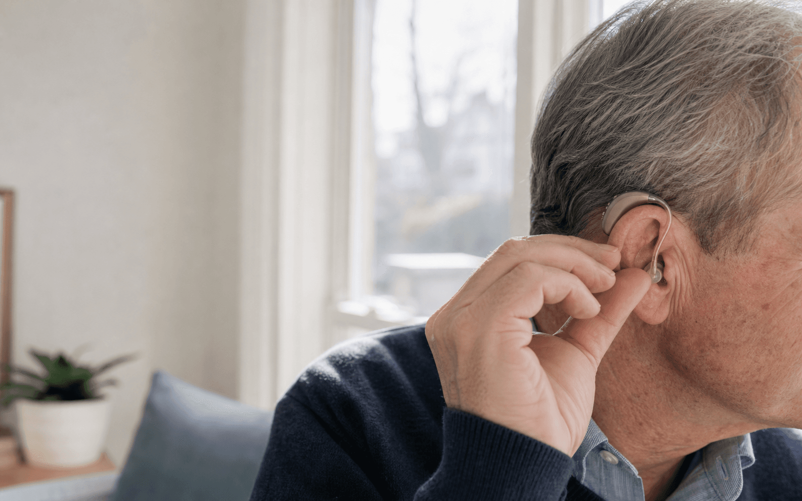 Adult adjusting a hearing aid comfortably at home